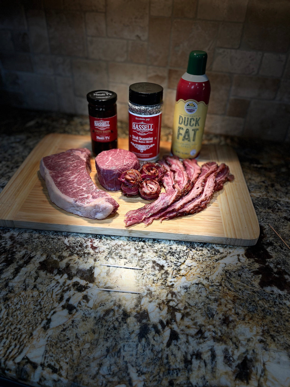 A curated selection of Hassell Cattle Company beef cuts, including new york strip and bacon arranged neatly, both part of the Sweetheart Deal, displayed on a rustic wooden background with a romantic touch
