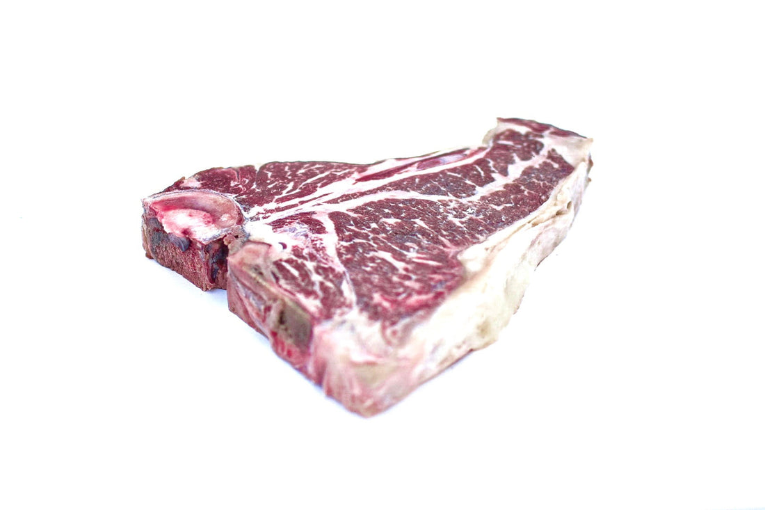 A thick, Hassell Cattle Company T-bone steak, showcasing its rich marbling and vibrant red color, placed on a clean, crisp white background.