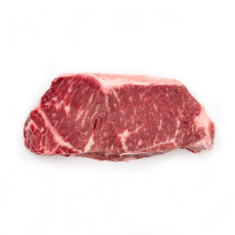 Gold NY Strip on butcher paper at a Texas backyard table for the Two Gold Strip Upgrade