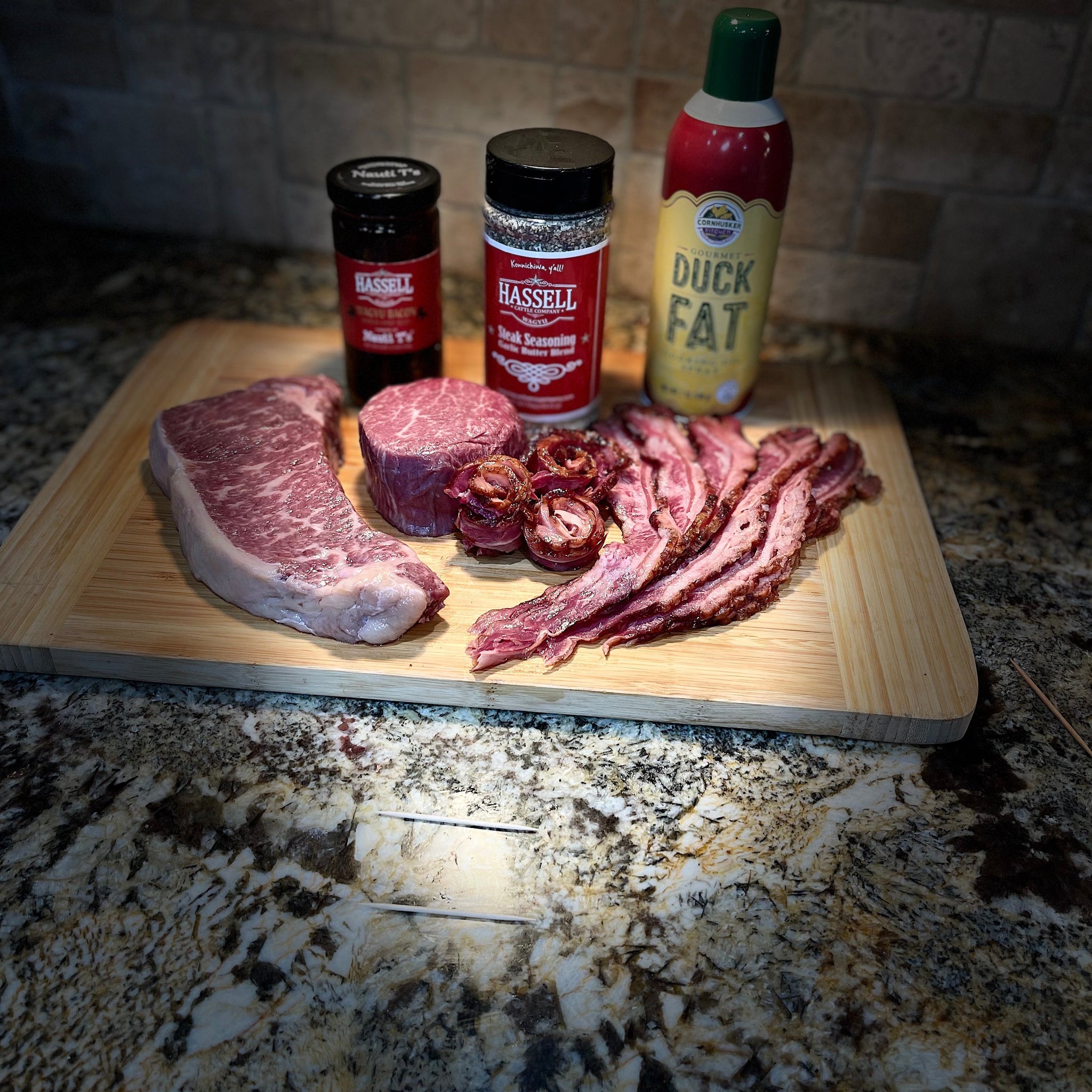 A curated selection of Hassell Cattle Company beef cuts, including new york strip and bacon arranged neatly, both part of the Sweetheart Deal, displayed on a rustic wooden background with a romantic touch