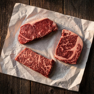 Steak Night Trio: a Premium NY strip, a Denver steak, and a Gold ribeye on butcher paper