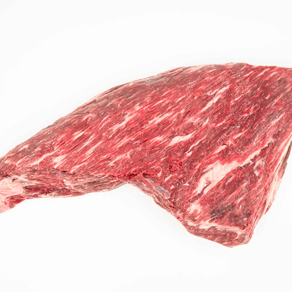 A well-marbled, boneless tri-tip cut of beef, showcasing its tender texture and rich red color, set on a clean, crisp white surface.